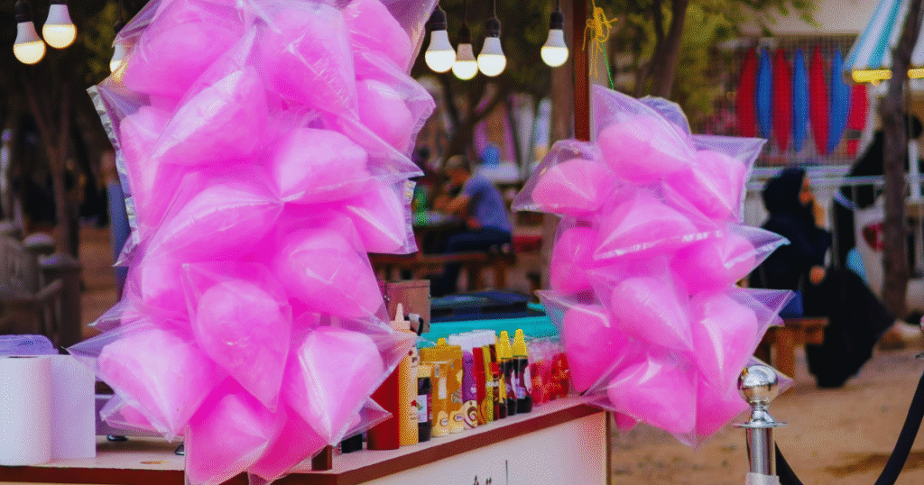 A colorful cotton candy stand adorned with pink balloons, inviting visitors to enjoy sweet treats at a festive event.