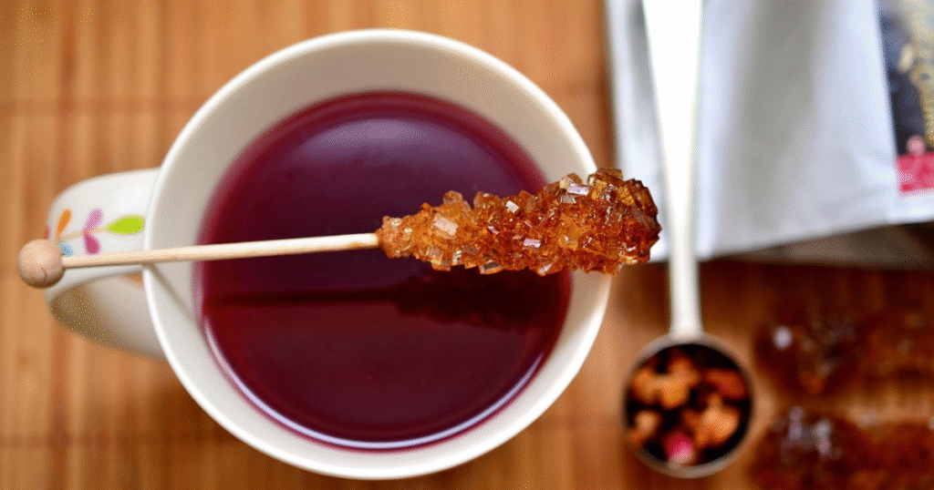 A cup of tea with a spoon resting inside, partially submerged, and another spoon placed beside it on a surface.
