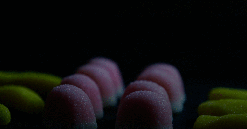 A cluster of candy corn pieces arranged on a smooth black surface, showcasing their vibrant orange, yellow, and white colors.