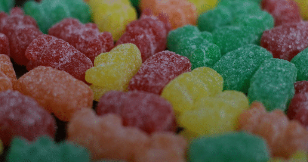 A close-up image featuring a pile of gummy bears in multiple colors, emphasizing their fun, chewy appearance.