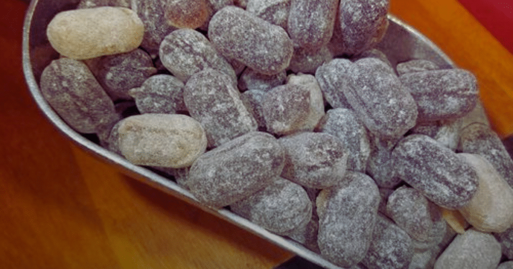 A bowl filled with chocolate-covered nuts sits on a wooden table, invitingly arranged for a snack.