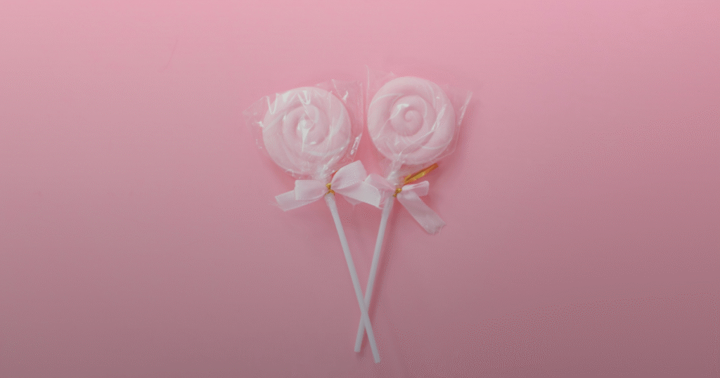 Two colorful lollipops resting on a vibrant pink background.
