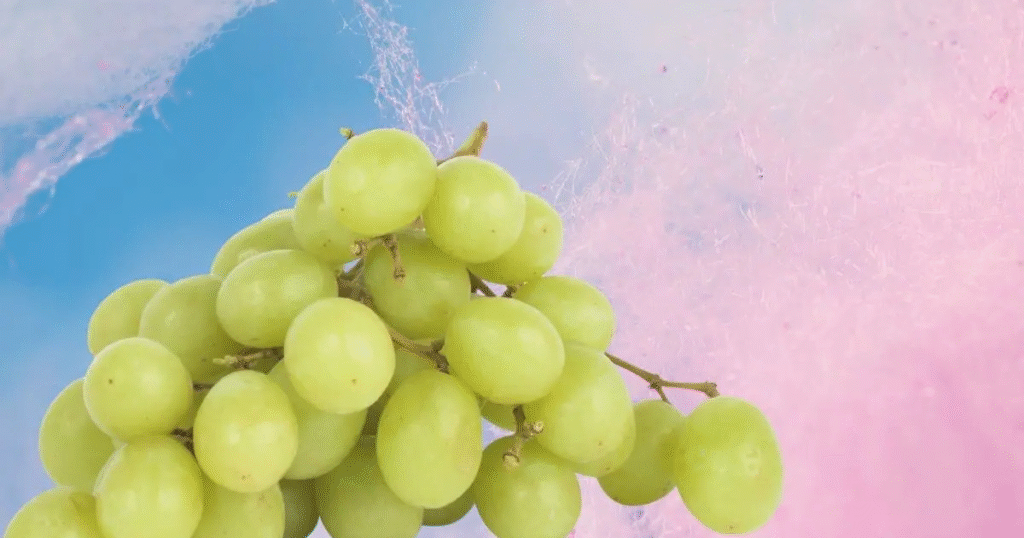 A cluster of grapes displayed against a vibrant blue and pink background.